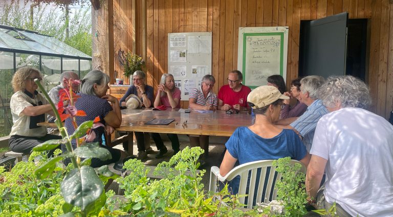 Le groupe de commanditaires, assis autour d'une table signant le cahier des charges au jardin du GAEC.