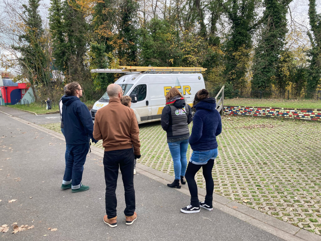 Plusieurs commanditaires à l’extérieur près d’un parking, en visite sur le site des 4Écluses.