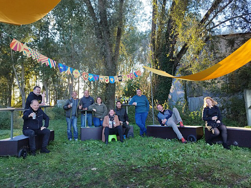 Le groupe de commanditaires posant à l’extérieur, sur des bancs dans l’herbe, lors de l’inauguration.