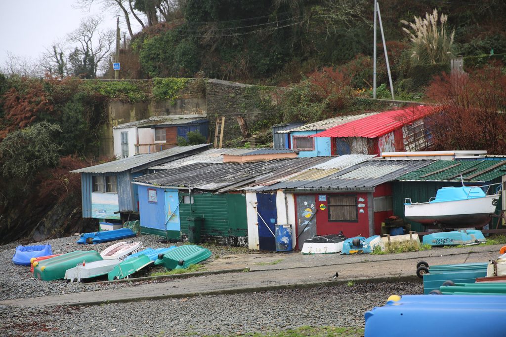 Une rangée de cabanes de pêcheurs colorées de Maison Blanche avec des annexes de bateau entreposés devant elles.