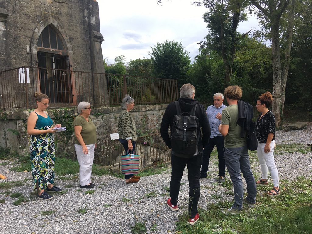 Le groupe de commanditaires se tenant autour de la chapelle Notre-Dame-de-Clairence lors d'une visite.