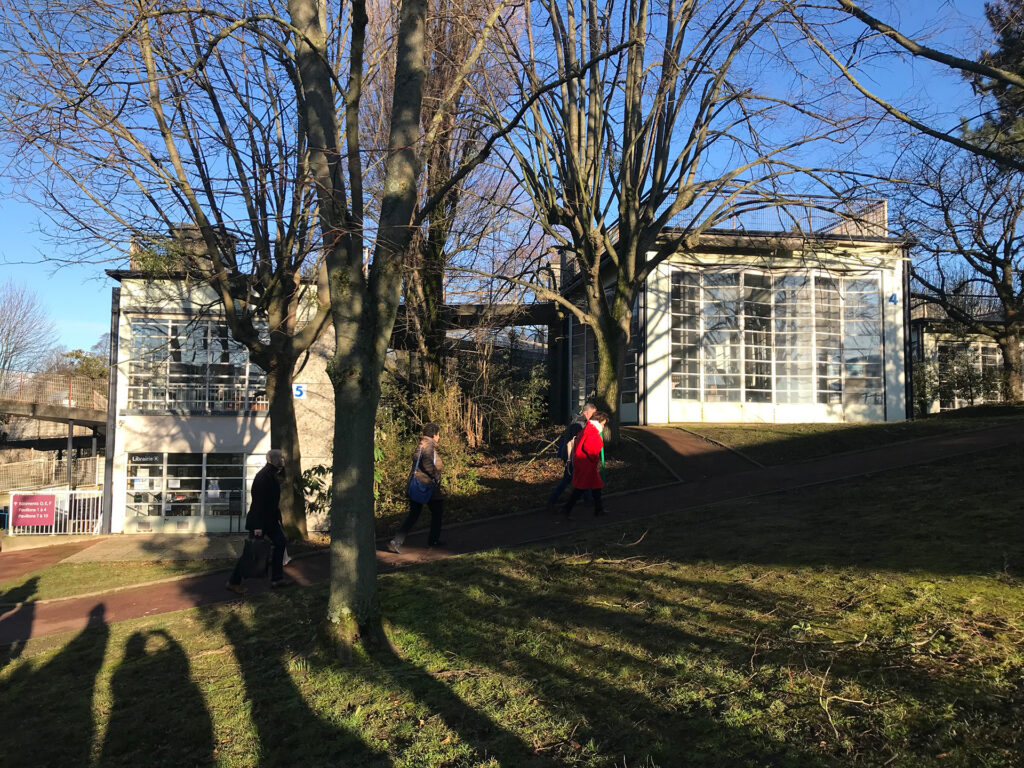 Dans l’enceinte du futur Musée Mémorial du Terrorisme, à l’extérieur, plusieurs personnes marchent sous les arbres