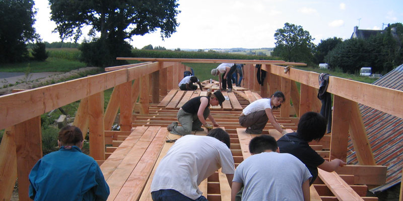 Un groupe de personnes s'attèle à la construction du sol de la passerelle.