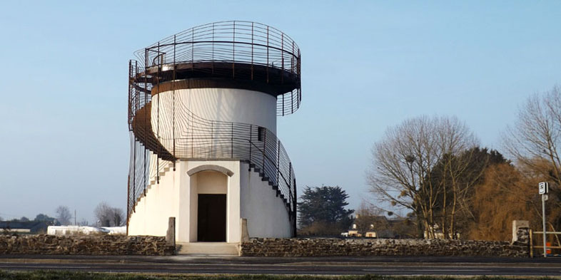 Le belvédère est visible de face. L'escalier montant au toit panoramique entoure le corps du moulin. Une entrée se trouve au rez-de-chaussée afin de pénétrer à l'intérieur.