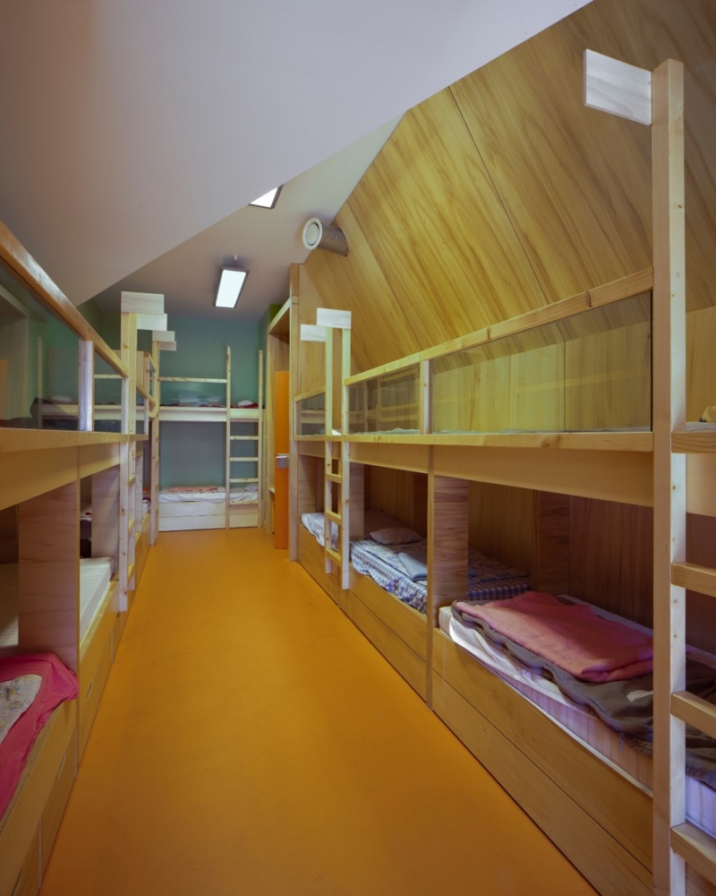 Des lits superposés dans des caissons de bois crées des zones de sieste pour les élèves.