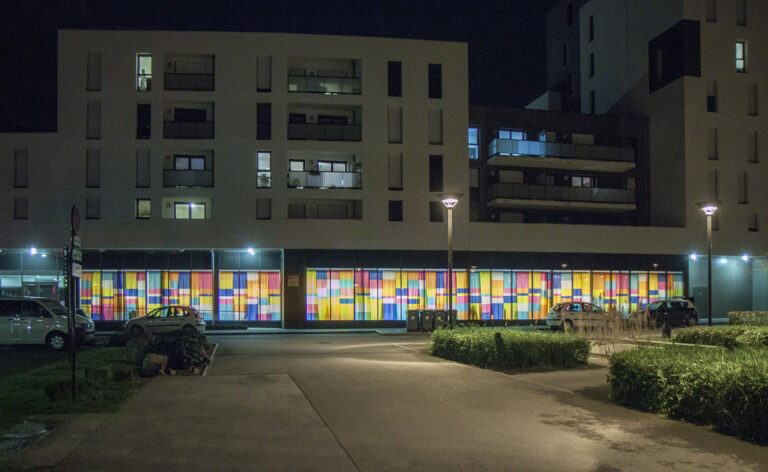 Le rideau recouvre toutes les fenêtres du rez-de-chaussée du bâtiment. Même la nuit, les couleurs sont visibles depuis la rue grâce à un éclairage qui balaye le rideau.