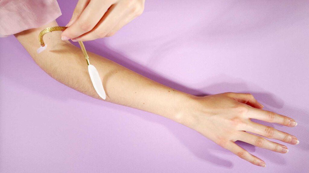 Plumes blanches montées en bijoux dorées pour caresser soi-même la peau.